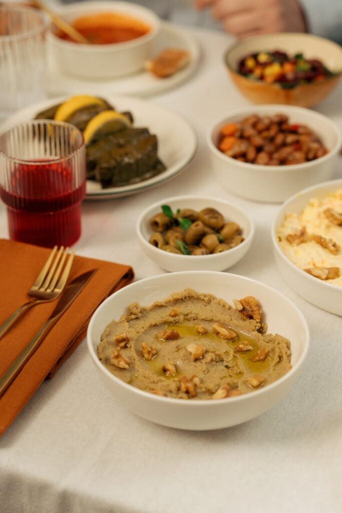 A variety of Mediterranean appetizers including baba ghanoush, olives, and dolmas on a set table.
